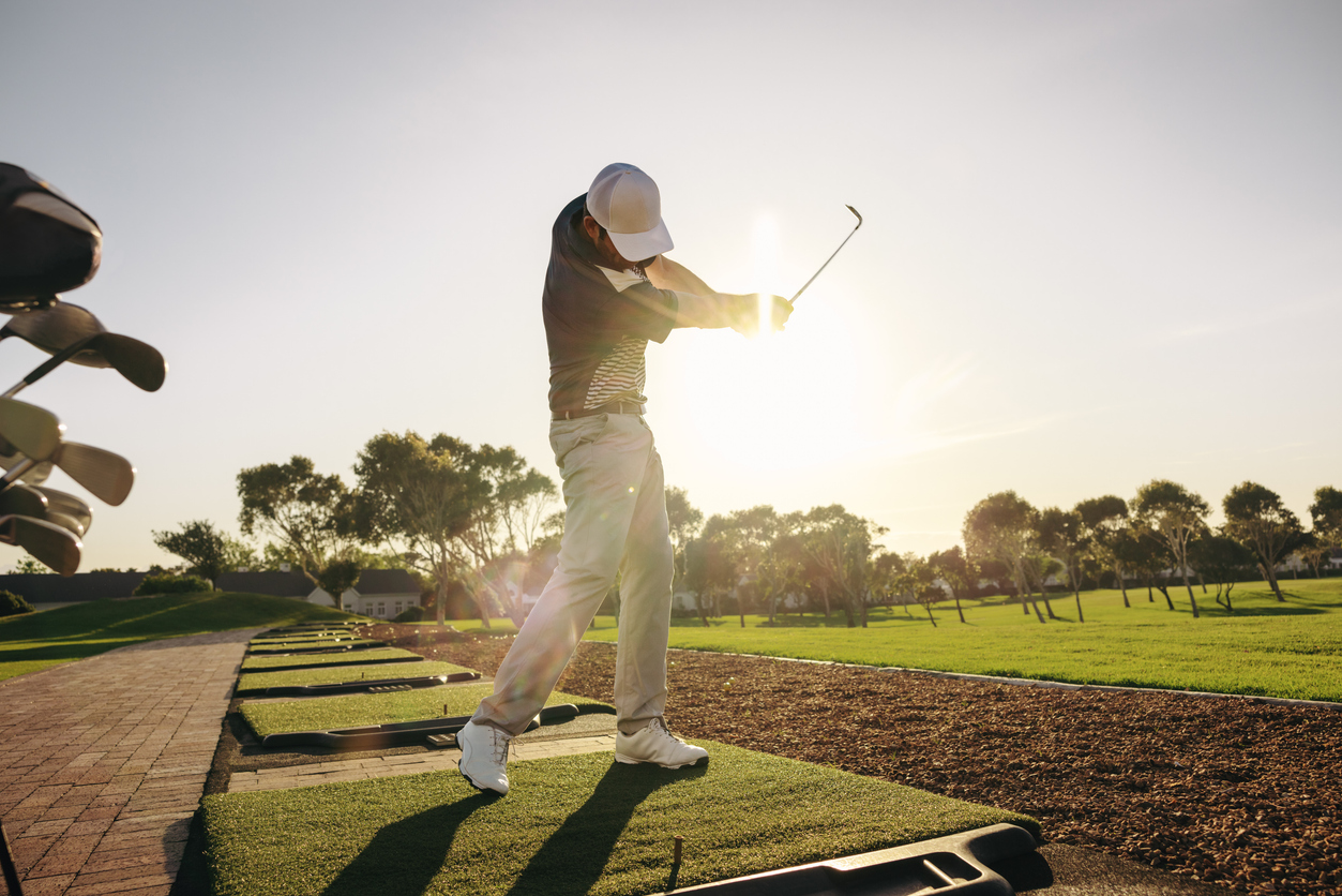  a golfer swinging under the sun in a golf course