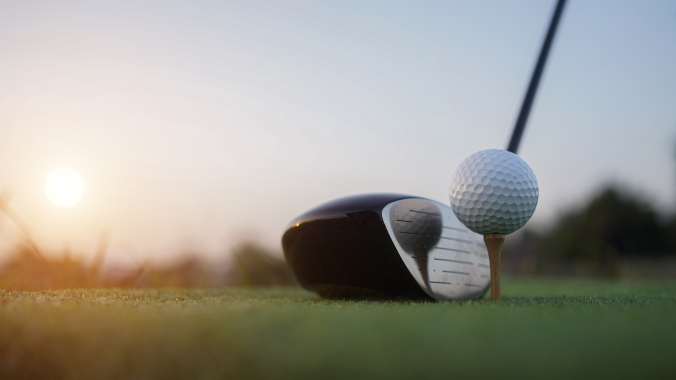 Golf clubs and balls on a green lawn in a beautiful golf course with morning sunshine. Close up of golf equipment on green grass