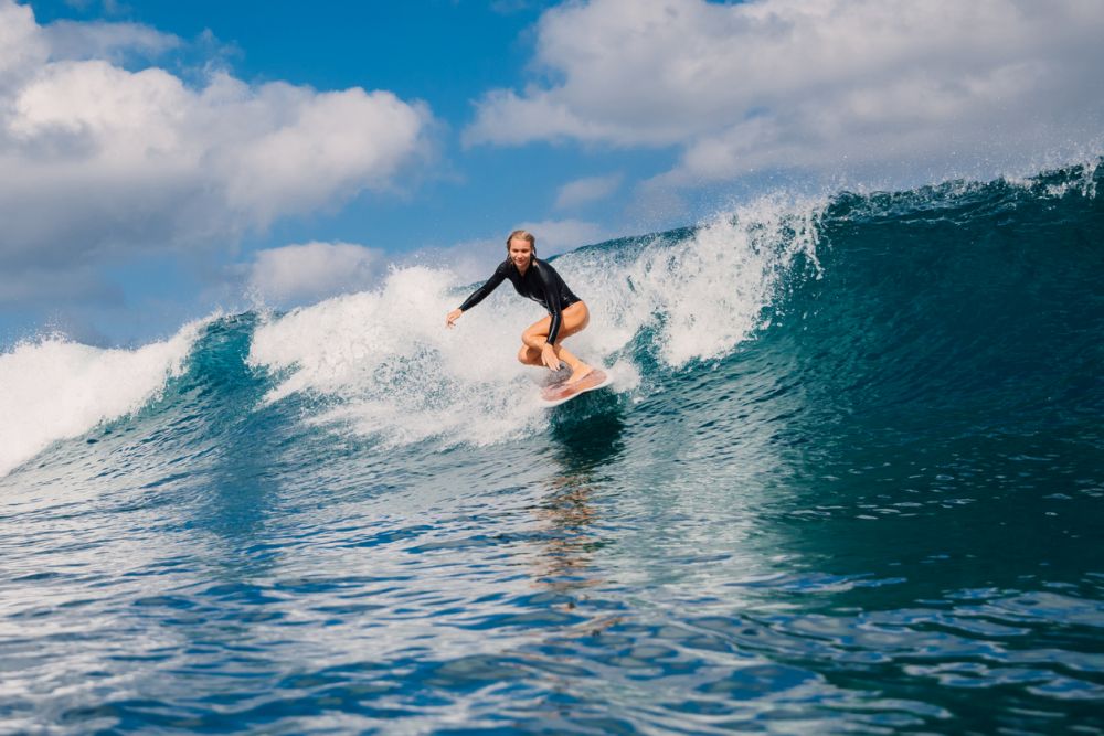 Woman surfer rides on crashing wave on a sunny day, surfing in ocean