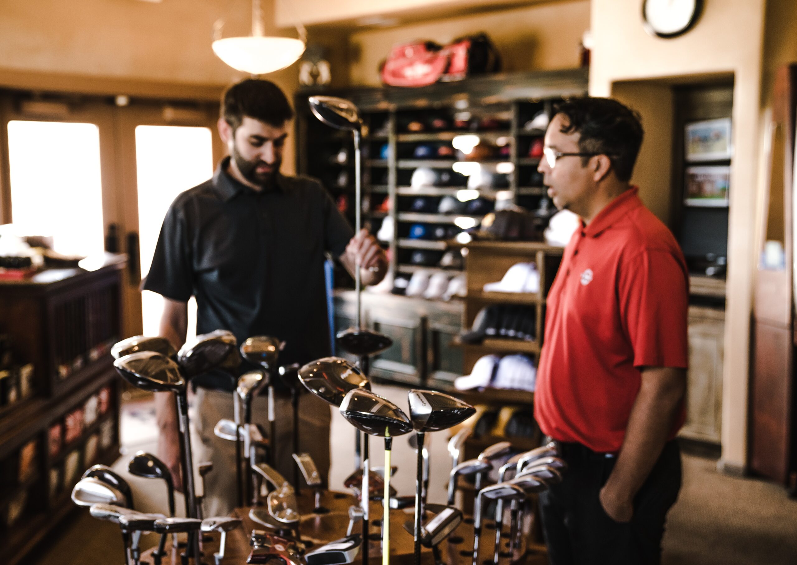 Guy purchasing golf clubs assisted by salesperson