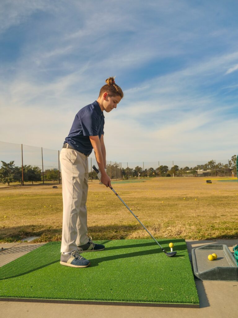 Young man playing golf on golf mat