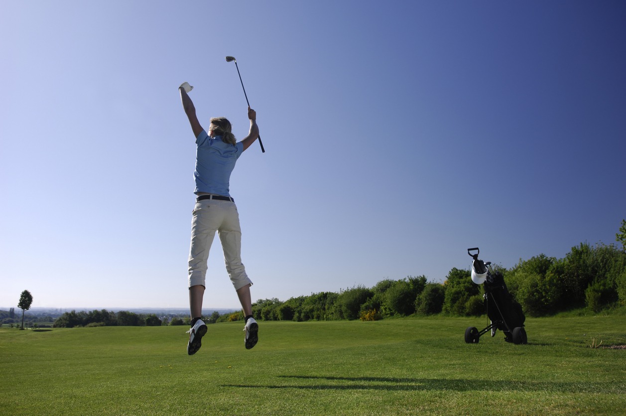 A golfer jumping up in celebration in a golf course