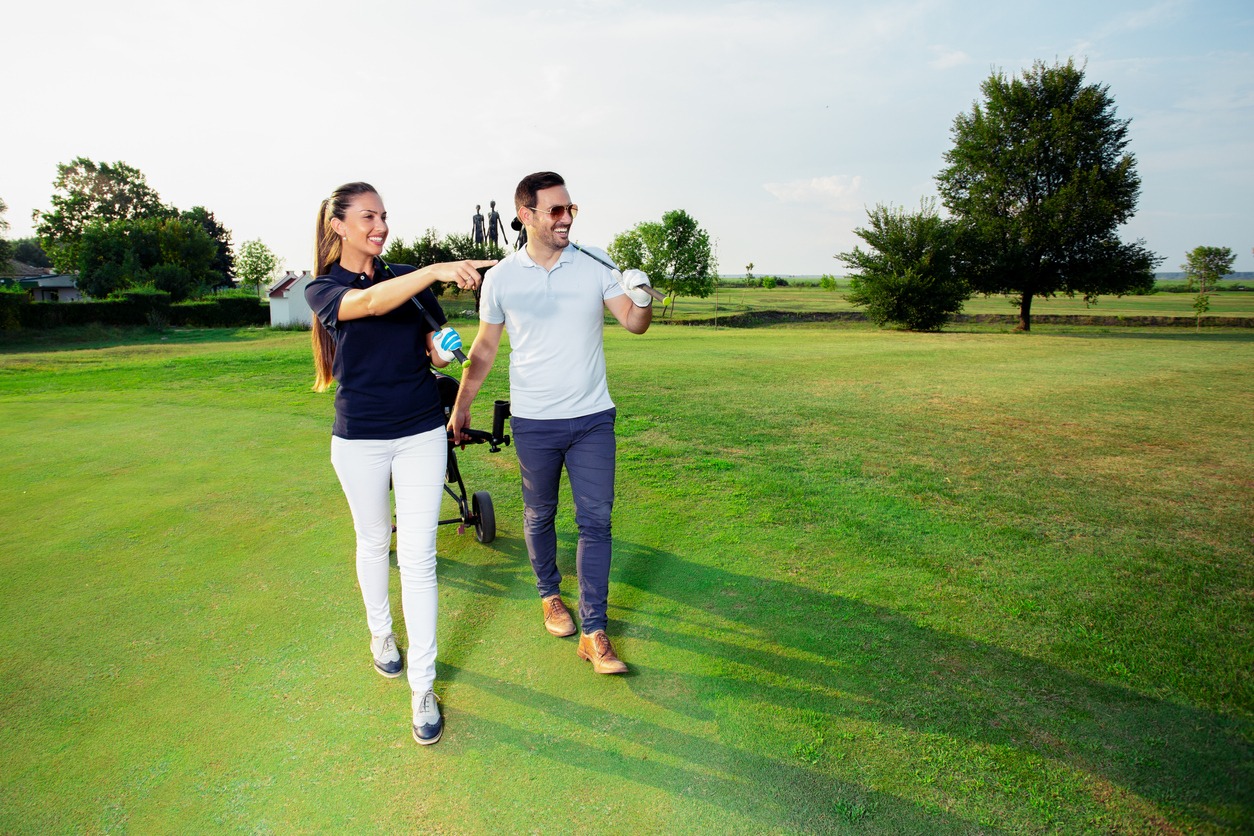 A man and woman walking in the golf course