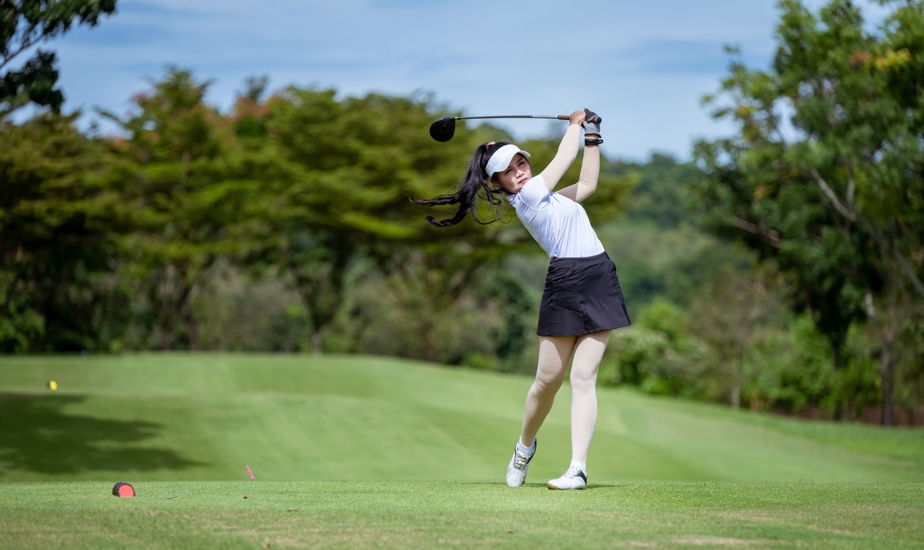 A woman teeing golf in tournament