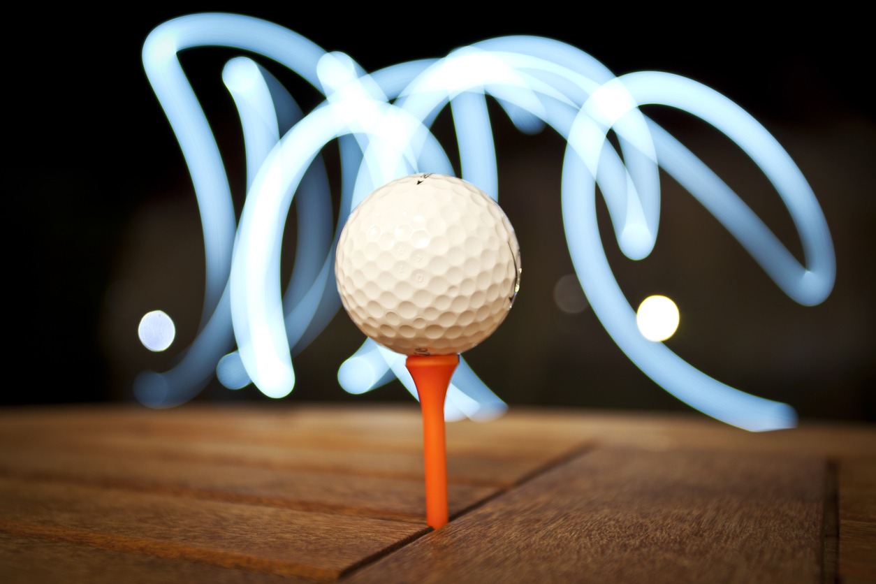 a golf ball illuminated by glowsticks in the background